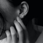 : A woman holding her ear with multiple piercings