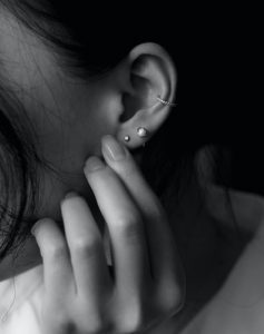 : A woman holding her ear with multiple piercings