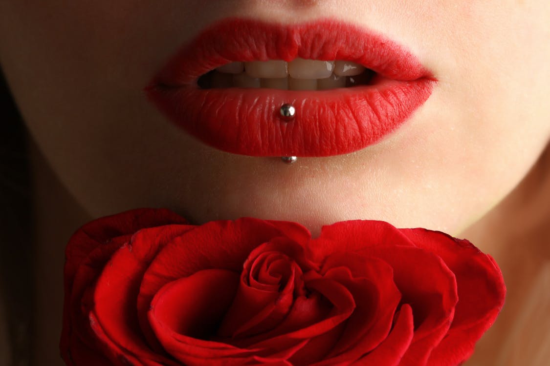 a woman with red lips and lip piercings.